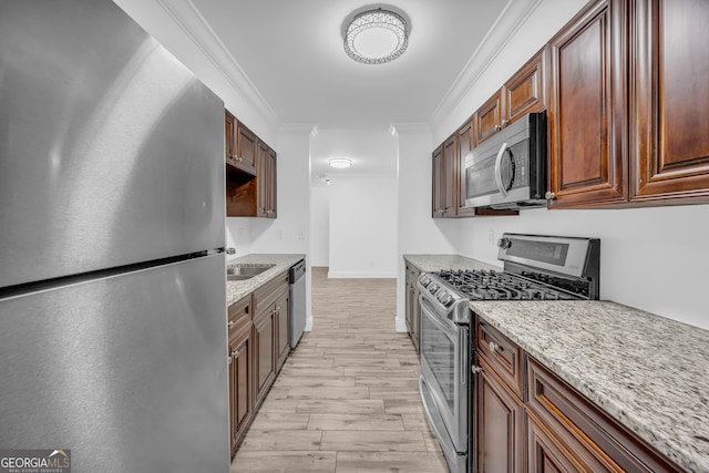 kitchen with stainless steel appliances, crown molding, a sink, light wood-type flooring, and light stone countertops