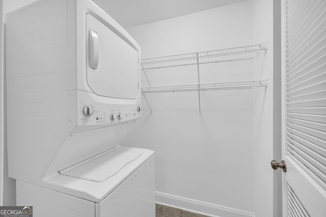 washroom with stacked washer / drying machine and baseboards