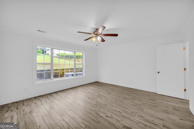 empty room with crown molding, wood finished floors, a ceiling fan, and baseboards