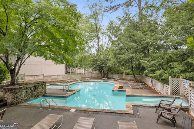 view of pool featuring a fenced backyard, a patio, and view of scattered trees
