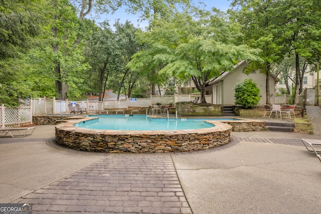 community pool featuring fence, a patio, and a jacuzzi