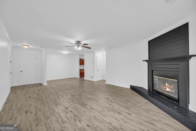 unfurnished living room with wood finished floors, a ceiling fan, crown molding, a large fireplace, and baseboards