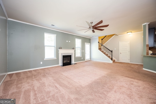 unfurnished living room with crown molding, a ceiling fan, stairs, carpet, and baseboards