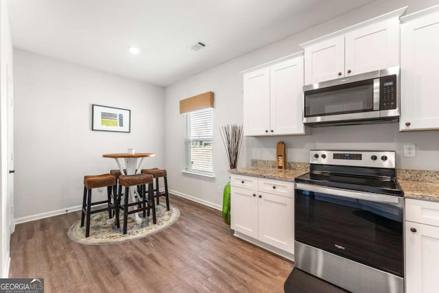 426 Samara Ct, Fairburn, GA 30213 - kitchen featuring stainless steel appliances, baseboards, wood finished floors, white cabinets, and light stone counters