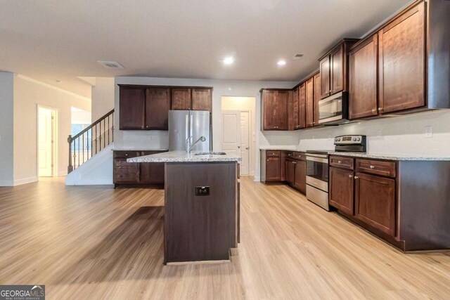 255 Dublin Way, Dallas, GA 30132 - kitchen with stainless steel appliances, a sink, light wood-type flooring, an island with sink, and light stone counters