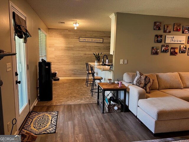 living area featuring wooden walls, dark wood-style flooring, healthy amount of natural light, a textured ceiling, and baseboards