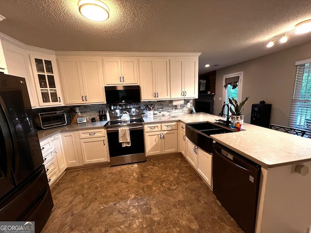 kitchen with black appliances, a peninsula, a textured ceiling, a sink, and decorative backsplash