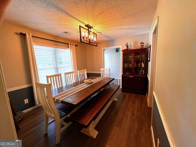 dining area with a chandelier, dark wood-style flooring, a textured ceiling, and baseboards