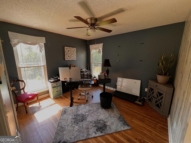 home office featuring a ceiling fan, a textured ceiling, wood finished floors, and baseboards