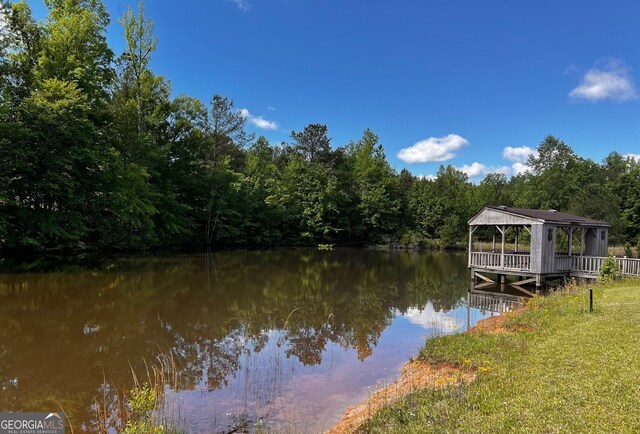 dock with a gazebo, a water view, and a view of trees