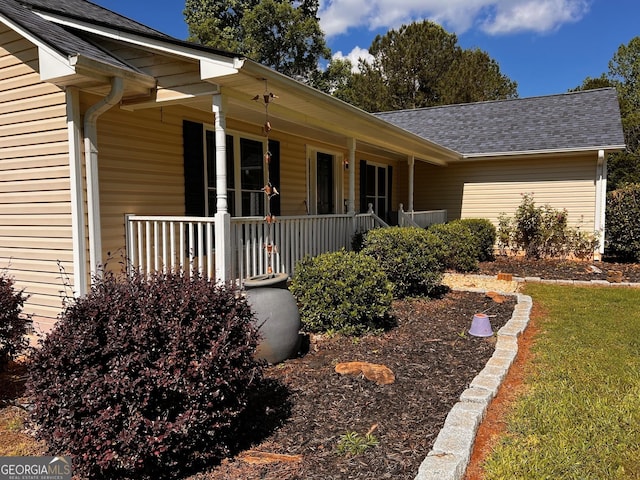 property entrance with a porch and roof with shingles