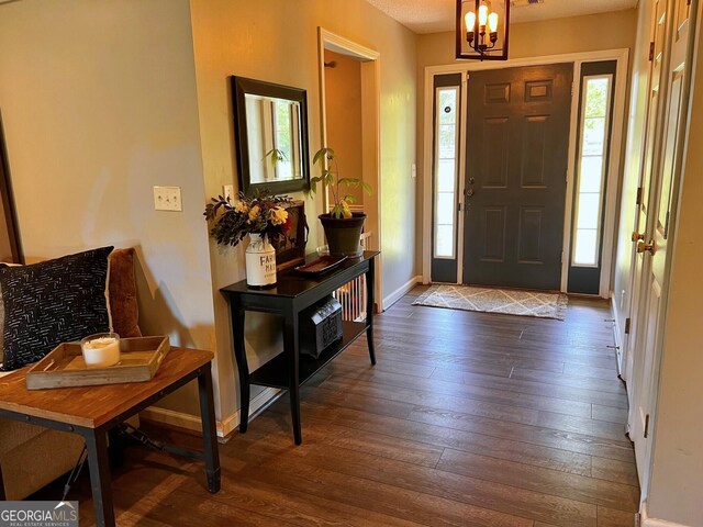 foyer entrance featuring hardwood / wood-style floors, a chandelier, and baseboards