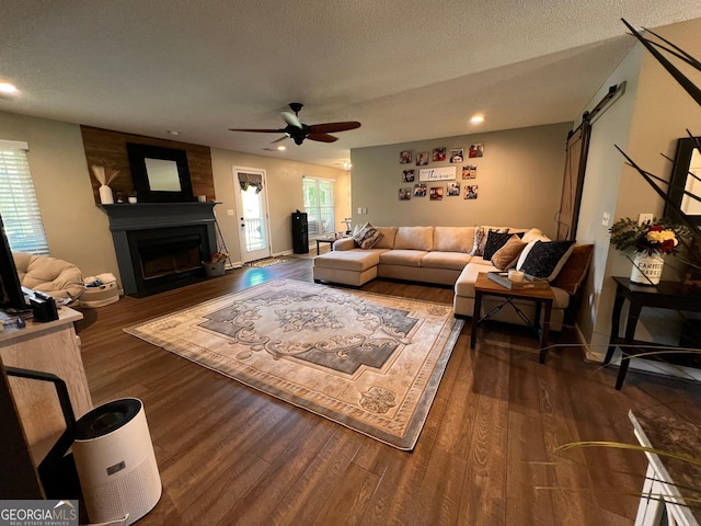 living room featuring a barn door, wood finished floors, a ceiling fan, a fireplace, and recessed lighting