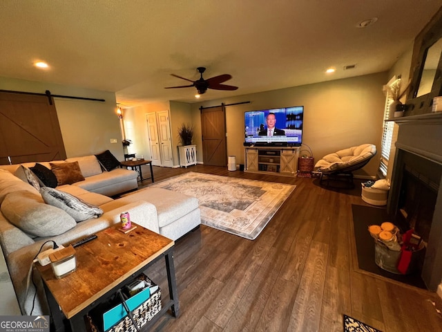 living room featuring a barn door, a fireplace, wood finished floors, recessed lighting, and ceiling fan