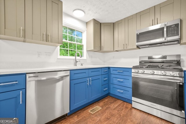1355 Tucker Woods Dr, Norcross, GA 30093 - kitchen featuring appliances with stainless steel finishes, a sink, a textured ceiling, light countertops, and dark wood finished floors