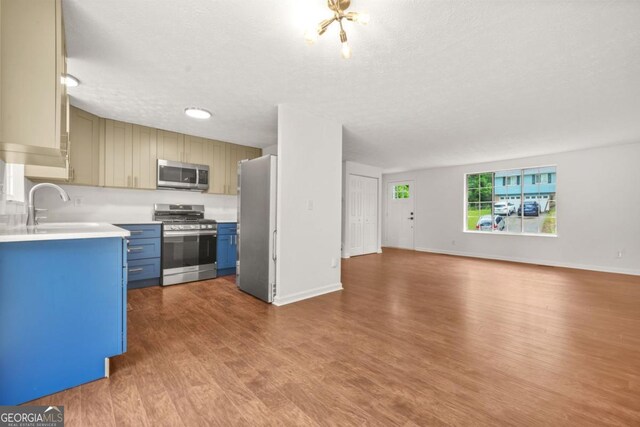 1355 Tucker Woods Dr, Norcross, GA 30093 - kitchen with stainless steel appliances, blue cabinets, open floor plan, light countertops, and dark wood finished floors