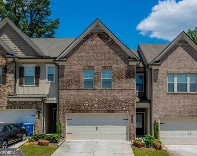 townhome / multi-family property featuring concrete driveway, brick siding, a garage, and board and batten siding