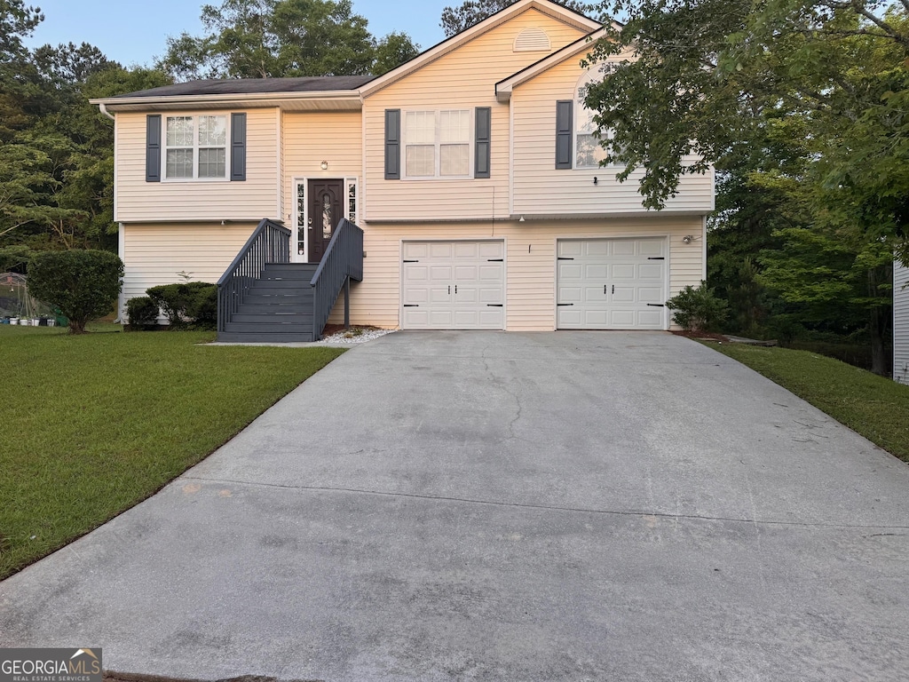split foyer home with asphalt driveway, an attached garage, and a front yard