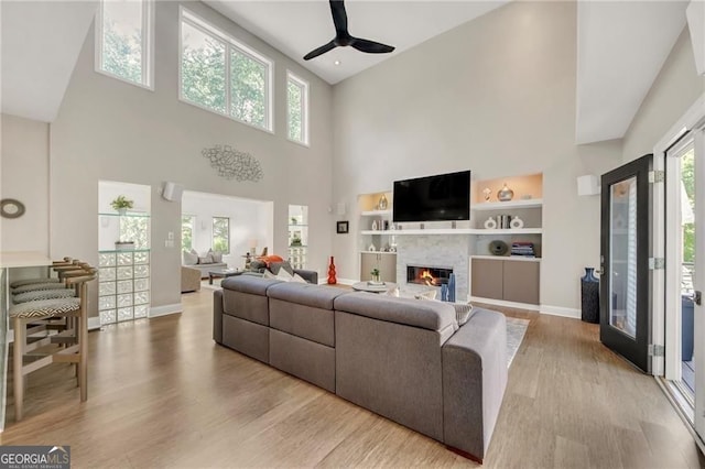 1420 Cortez Ln NE, Atlanta, GA 30319 - living area with a high ceiling, ceiling fan, a glass covered fireplace, wood finished floors, and built in shelves