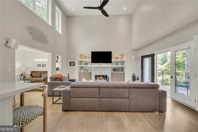 1420 Cortez Ln NE, Atlanta, GA 30319 - living area with a towering ceiling, ceiling fan, a glass covered fireplace, light wood-style floors, and built in features