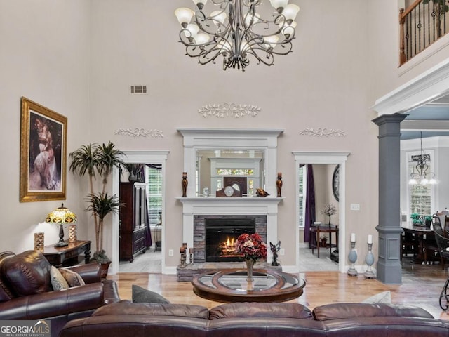 124 Belford Way, Locust Grove, GA 30233 - living area with a chandelier, a towering ceiling, decorative columns, a fireplace, and wood finished floors