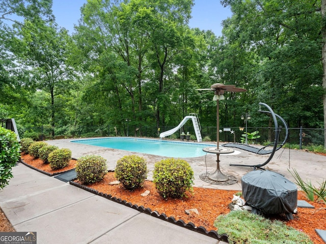 124 Belford Way, Locust Grove, GA 30233 - outdoor pool with a water slide, a patio, and view of wooded area