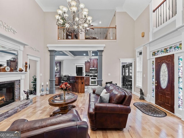 124 Belford Way, Locust Grove, GA 30233 - living area featuring a towering ceiling, wood finished floors, a fireplace, a chandelier, and decorative columns
