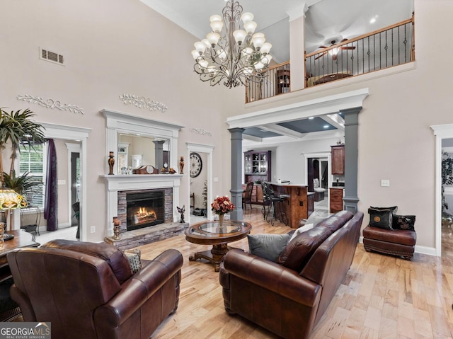 124 Belford Way, Locust Grove, GA 30233 - living area with ornate columns, a towering ceiling, light wood-style flooring, and a fireplace