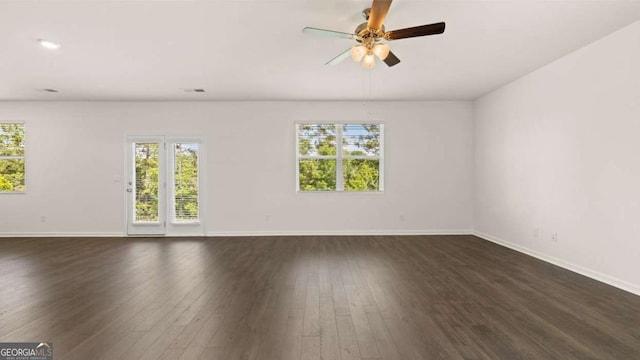 spare room with plenty of natural light, dark wood finished floors, baseboards, and a ceiling fan