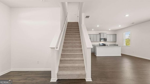 stairway with wood finished floors, baseboards, and recessed lighting