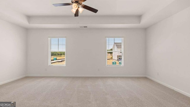 unfurnished room featuring carpet flooring, a raised ceiling, and ceiling fan