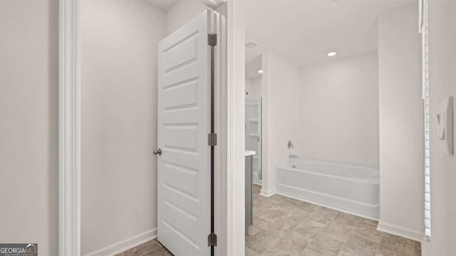 bathroom with a garden tub and baseboards