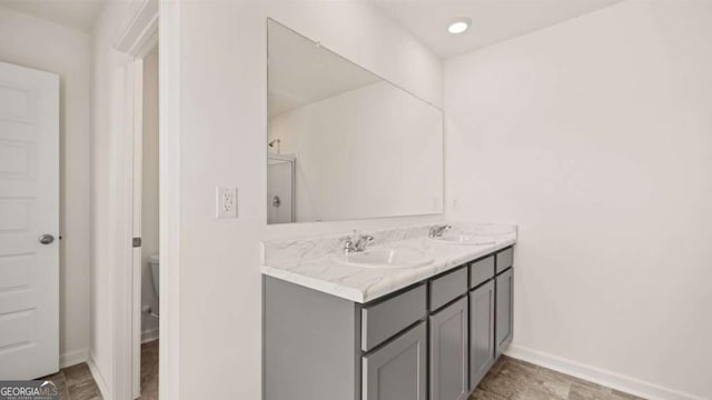 full bath featuring double vanity and baseboards