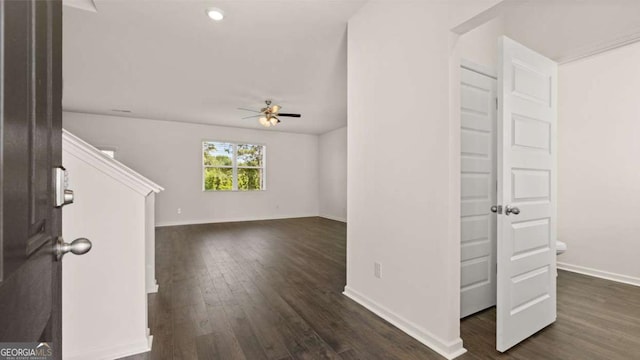 unfurnished living room with ceiling fan, dark wood-style flooring, and baseboards
