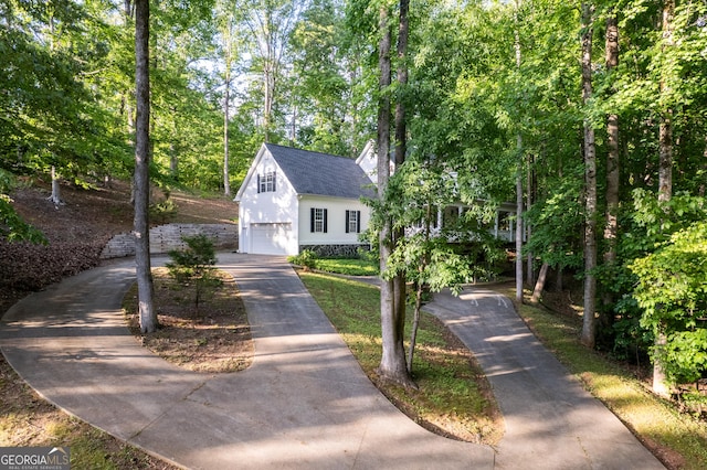 view of front facade featuring an attached garage, driveway, and view of wooded area