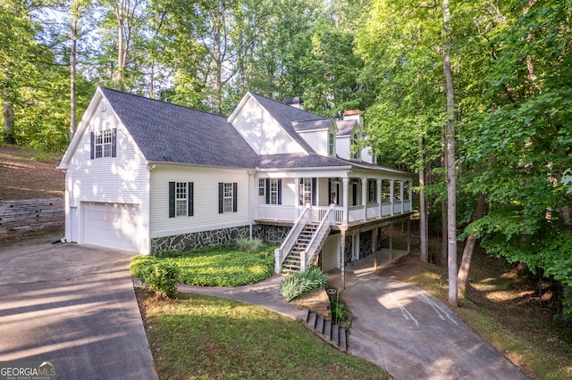 view of front of property featuring asphalt driveway, an attached garage, a shingled roof, a chimney, and stairs