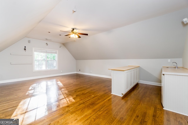 bonus room featuring wood finished floors, a ceiling fan, a sink, vaulted ceiling, and baseboards