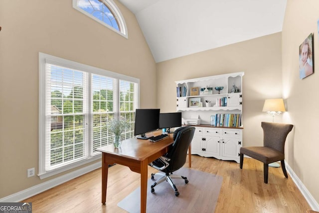 home office with high vaulted ceiling, light wood-style floors, and baseboards
