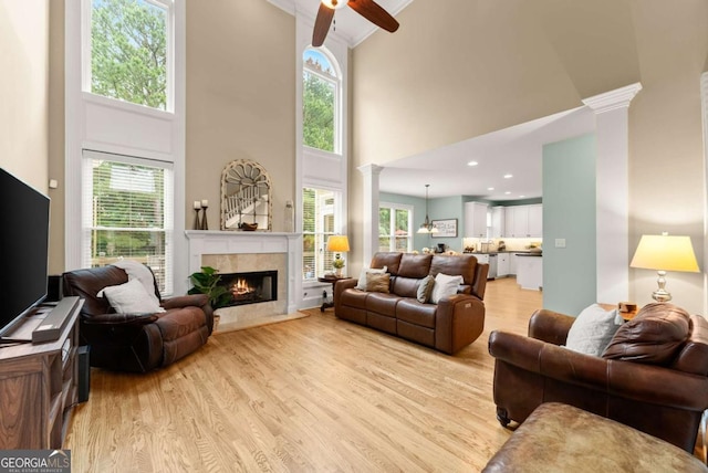 1721 Mulberry Lake Dr, Dacula, GA 30019 - living room featuring decorative columns, a towering ceiling, light wood-style flooring, a fireplace, and ceiling fan