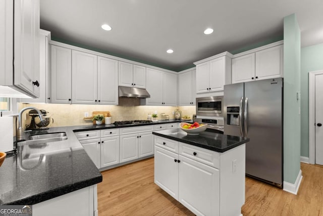 kitchen with appliances with stainless steel finishes, under cabinet range hood, a sink, white cabinetry, and recessed lighting