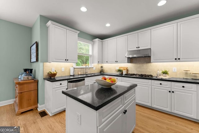 kitchen with under cabinet range hood, stainless steel appliances, a sink, light wood-type flooring, and white cabinets