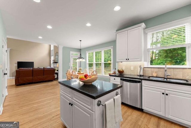 kitchen featuring a sink, stainless steel dishwasher, white cabinets, decorative backsplash, and light wood finished floors