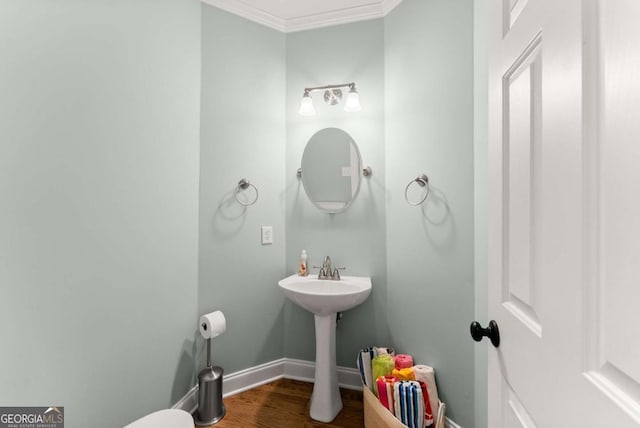 half bathroom featuring crown molding, wood finished floors, and baseboards