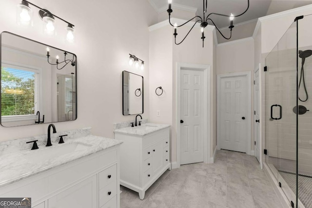 bathroom with a chandelier, ornamental molding, a stall shower, and two vanities
