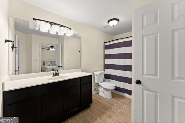 ensuite bathroom featuring a ceiling fan, wood finished floors, vanity, baseboards, and toilet