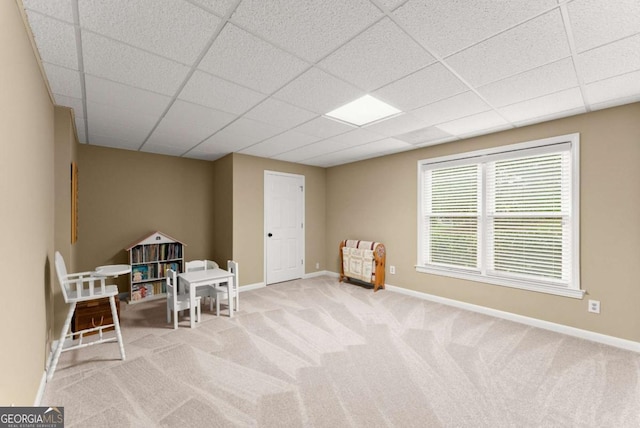 living area featuring a drop ceiling, carpet floors, and baseboards