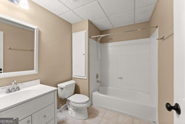 full bath featuring tile patterned flooring, toilet, vanity, shower / washtub combination, and a drop ceiling