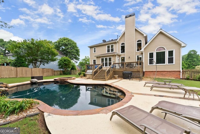 view of pool with a wooden deck, a fenced backyard, a patio, and a pool with connected hot tub