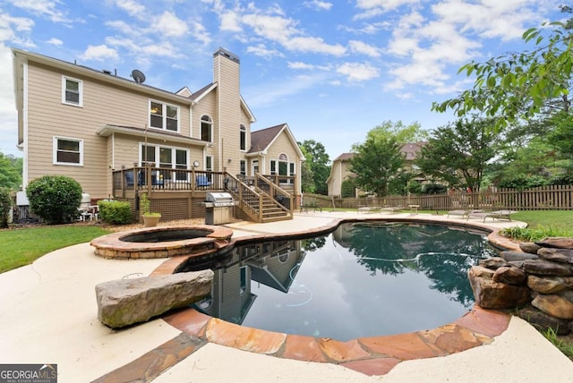view of pool featuring a wooden deck, fence, a patio area, and a pool with connected hot tub