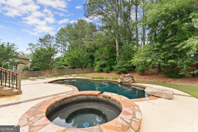 view of pool featuring a patio, a pool with connected hot tub, and fence